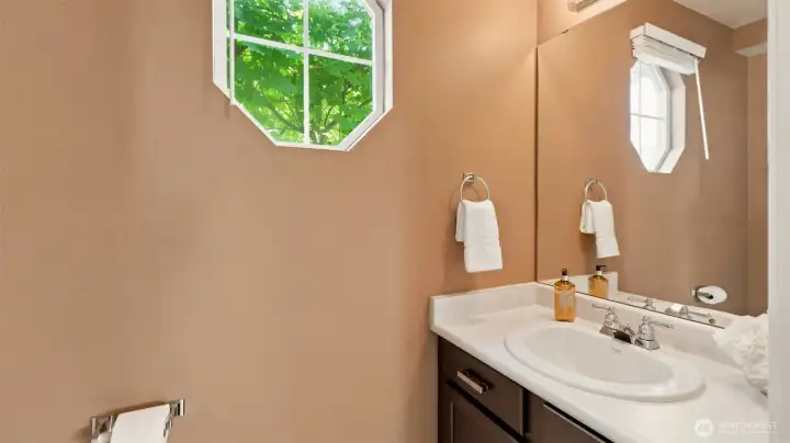 Convenient main-floor powder room with pedestal sink and natural light, large vanity and decorative window. Convenient main-floor powder room with pedestal sink and natural light, large vanity and decorative window.