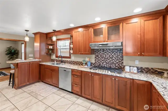 Chef’s kitchen with gas range, stainless appliances, and double oven.