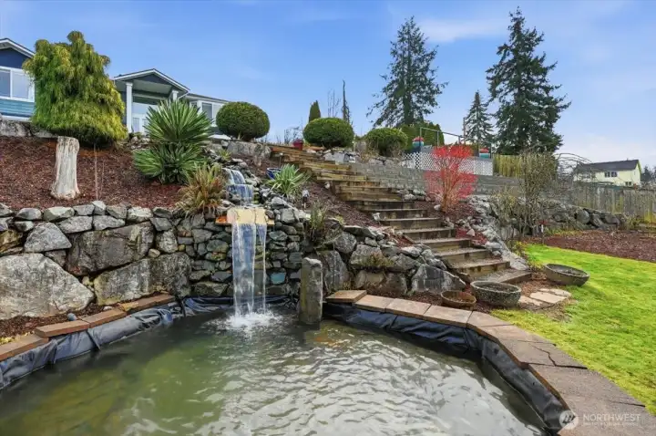 This impressive front-yard water feature creates an unforgettable first impression. Crystal-clear water cascades over natural stone, surround by lush landscaping.