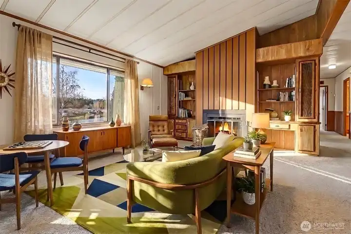 Family room features vaulted ceilings, picture window with lake views and a wood fireplace with built in bookshelves.  Virtually staged photo