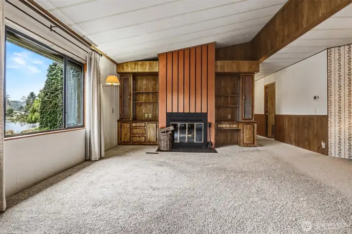 Family room features vaulted ceilings, picture window with lake views and a wood fireplace with built in bookshelves.  Opens to the Kitchen.