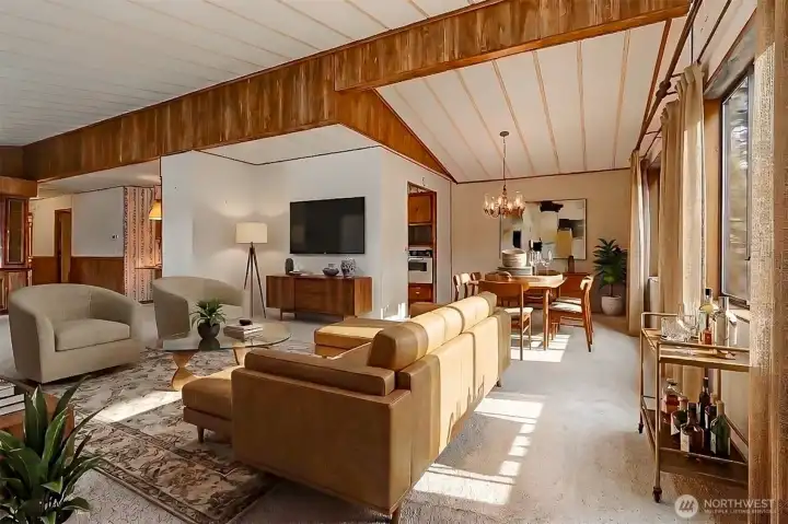 Living room with vaulted ceilings and picture window with a lake view opens to the dining room.  Virtually staged photo.