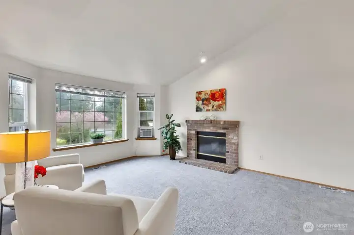 Open living room with vaulted ceilings, bay window.