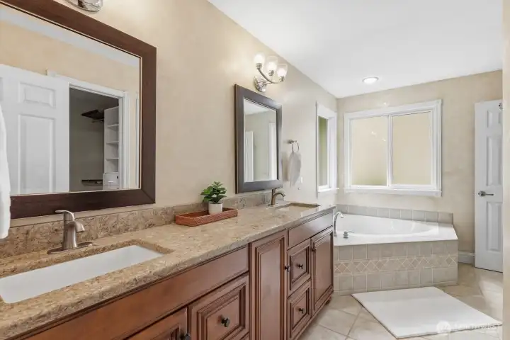 Primary bathroom with walnut slab granite vanity and tiled floor. Primary bathroom with walnut slab granite vanity and tiled floor.