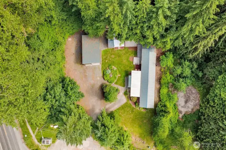 Aerial overview highlighting the home, detached shop, driveway, and surrounding grounds.