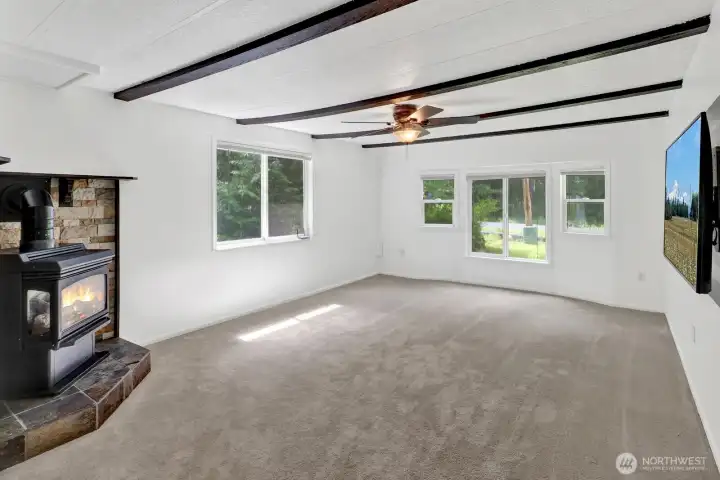 Spacious living room featuring a propane fireplace, vaulted ceiling, and large windows.