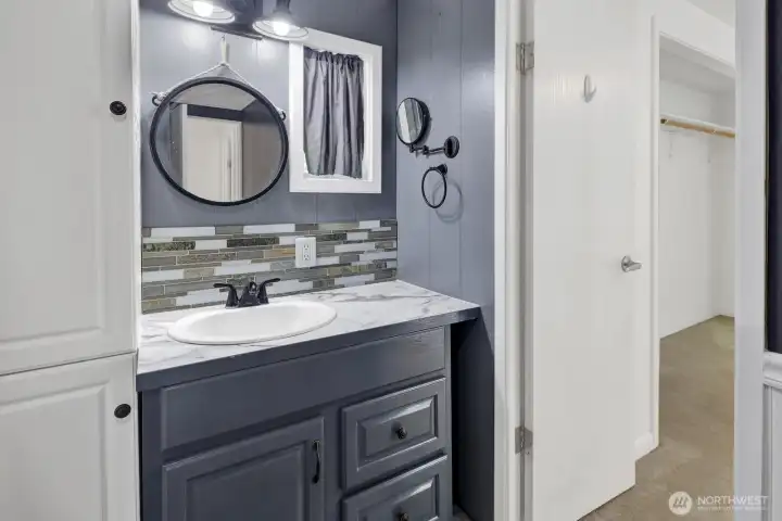 Updated bathroom featuring modern vanity, storage, and fixtures.
