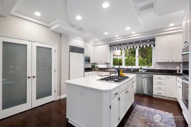 The chef’s kitchen boasts a quartz island with a round veg/prep sink with disposal, Viking 6 burner gas stove, stainless steel microwave, Sub-Zero refrigerator, double ovens, pantry and intricate ceiling details.