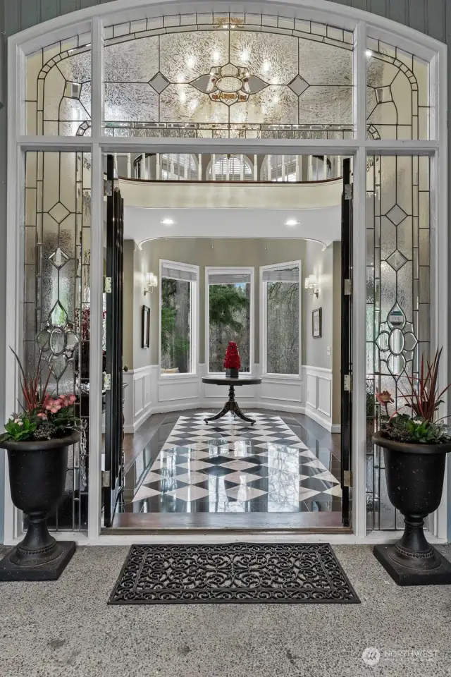 The covered front double door entry leads toward the inviting foyer with an Empire style crystal chandelier with Art Deco marble inlay that opens into a domed alcove outlined with tall windows and lake view.