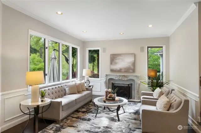 The formal living room off to the left features a marble surround gas fireplace with imported French stone mantle, hardwood floors, wainscoting, crown molding and lake views.