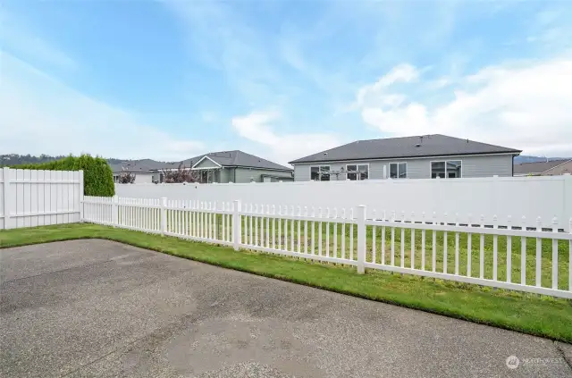 The private patio is enclosed with white vinyl picket fencing, offering a charming view of the green space between homes for added privacy and serenity.