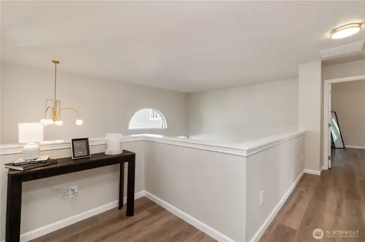 The upstairs landing provides a view of the living area, which features large windows.
