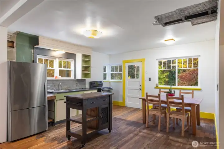 Kitchen AS-IS. on Main level traditional farmhouse door & windows overlooking the garden sanctuary, previously with outdoor  deck. Ceiling in photo is where a leak  is presenting from upper deck.