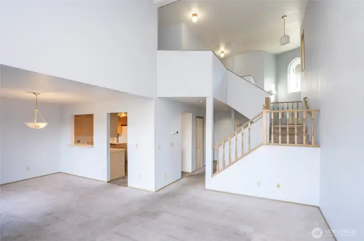 Open living room view into the kitchen, with a stairway leading to the three bedrooms upstairs.