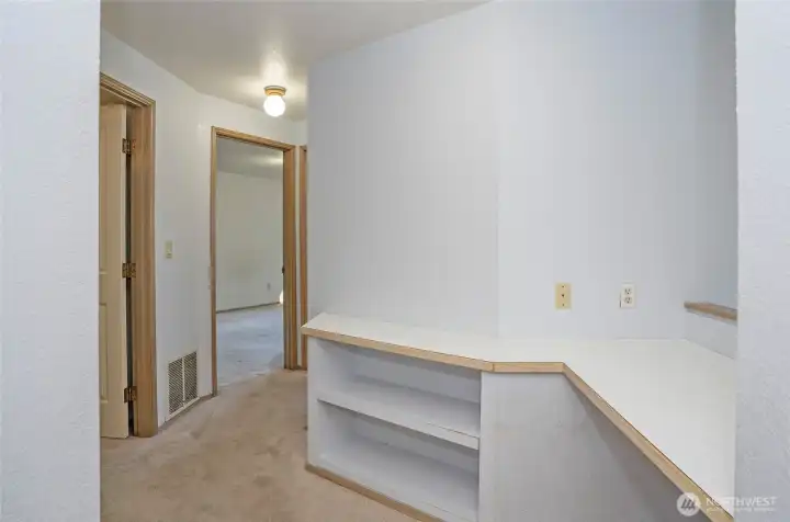 Alternate view of the upper landing with functional desk space and a hallway leading to the upper bedrooms.