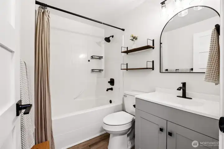 Upstairs hallway full bathroom- the darker fixtures and door handles, stylish mirror, update lighting add to the farmhouse feel of this home.