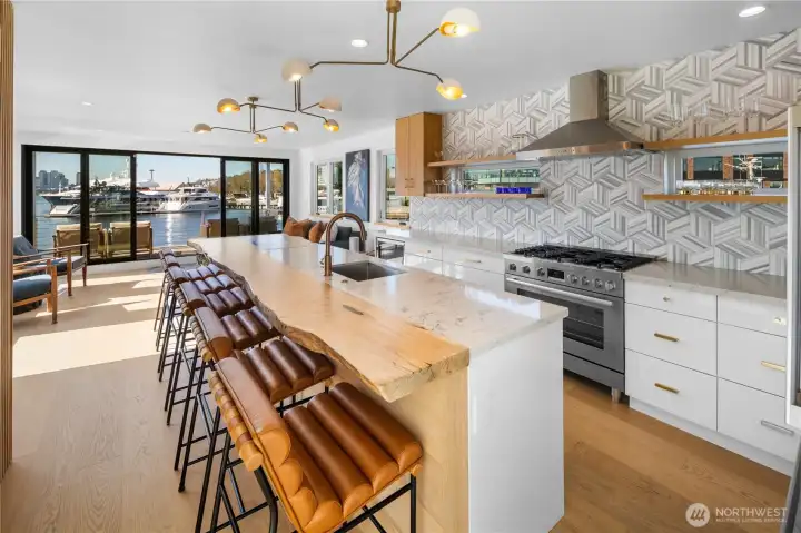 The upper level is the heart of the home, showcasing an open-concept kitchen & living space anchored by a striking oversized custom live-edge oak island. Expansive wall sliders fully open to a heated view deck with stunning, unobstructed city & lake vistas.