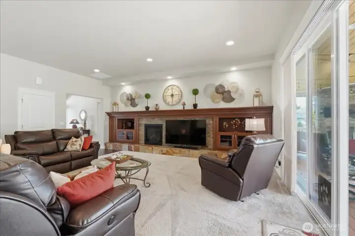 The living area is adjacent to the outdoor living area and can become one area with the opening of the sliding glass door.  Notice the recessed lighting that spotlights the fireplace mantle.