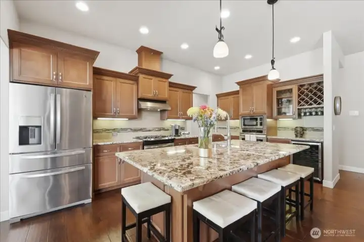 The chef’s kitchen showcases granite countertops, 8 foot island, full tile backsplash, double ovens, a 36 bottle wine refrigerator, and  custom soft close cabinetry with pull-outs.