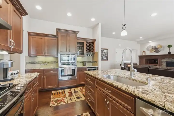 More storage with the electric oven, microwave and 36-bottle wine fridge along with built-in wine rack.  To the left is the hallway with walk-in pantry, another storage closet, and the hallway to the 4-car garage.