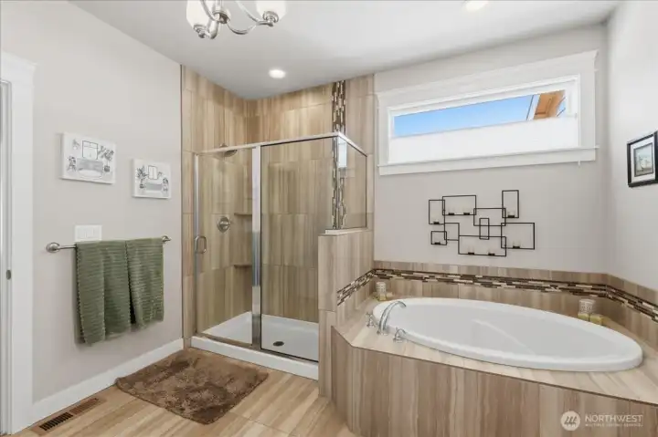 The primary bathroom with fully tiled shower and soaking tub.  You get the morning light, but if you want to adjust the light or privacy you have a roll-up shade.