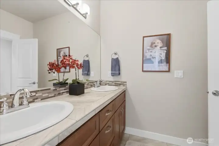 Main bathroom with dual sinks and separate area with walk-in shower and toilet.