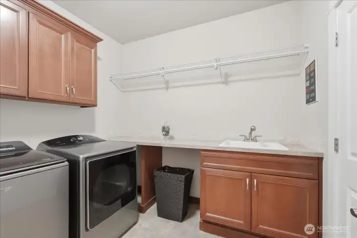 Laundry room with utility sink, storage and folding counter.  The washer and dryer stay with the home.