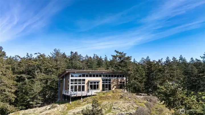 Anchored atop a rocky bluff sits a striking modern home with views of Lopez Island's Outer Bay, islands near and far, and the ever-changing waters of the Salish Sea.