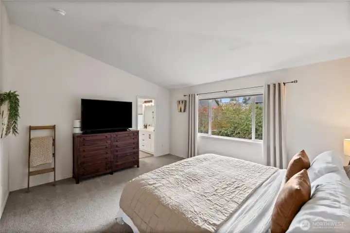 Retreat to a spacious primary suite overlooking the peaceful backyard landscape.