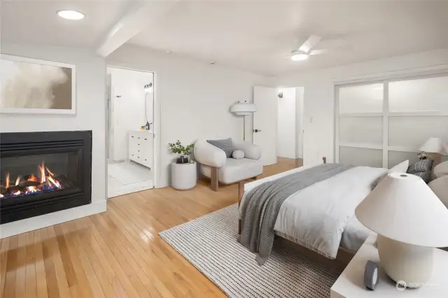 The main floor primary suite features gorgeous hardwood flooring, handsome gas fireplace and shoji-look glass sliding closet doors for a wonderfully updated luxe look.