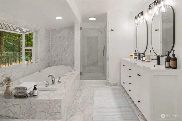 Inside the primary suite bathroom you are met with a 5-piece collection of updated amenities including the tile-surround glass shower and jetted tub with a deep garden bay window overlooking the water and forested view.