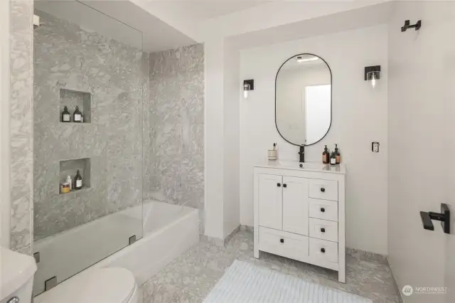 This main bathroom has been thoughtfully updated with contemporary black fixtures and classic white vanity.