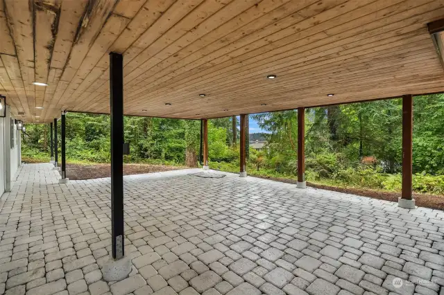 The plank ceiling of the covered stone patio is well lit with recessed lighting, providing a separate outdoor living space accessible from the lower level of the home, and large enough for big gatherings no matter the weather!