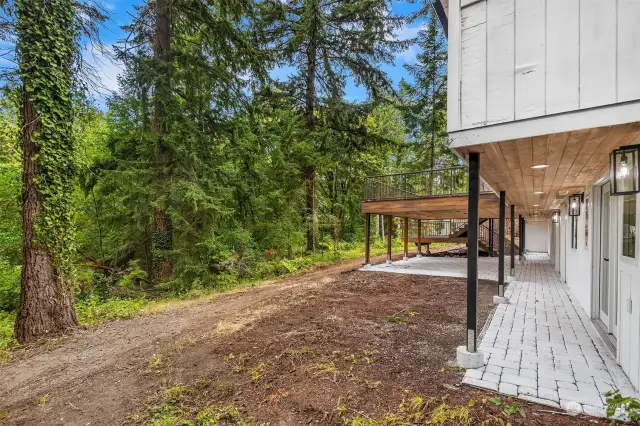 Well lit, and covered from weather, the walkway leads from the downstairs to the covered patios, all overlooking the natural treeline at the end of the yard.