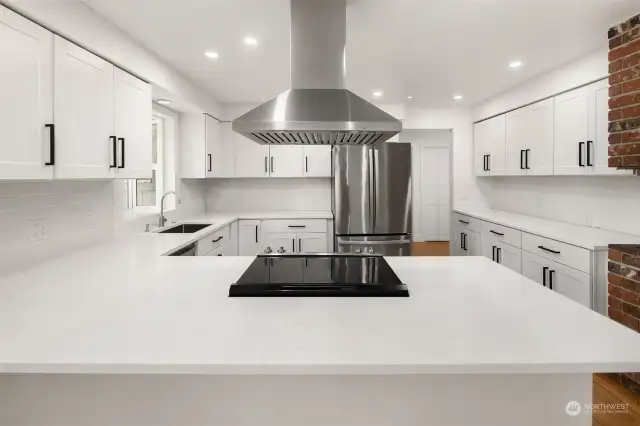 Room for up to 4 adults at the peninsula breakfast bar is a great place to keep chef company while whipping up the meal, and the long beverage/baking center along the right wall gives room for multiple cooks to share this updated quartz kitchen space.