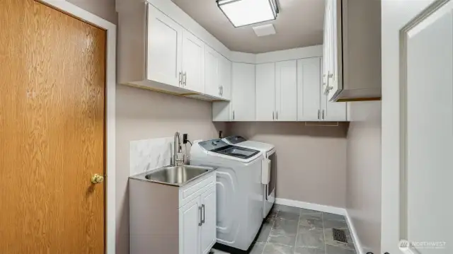 This modern laundry room offers plenty of cabinet storage, a convenient sink, and the washer and dryer stay!