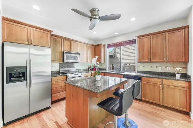 The kitchen features granite countertops, stainless steel appliances, and high ceilings.