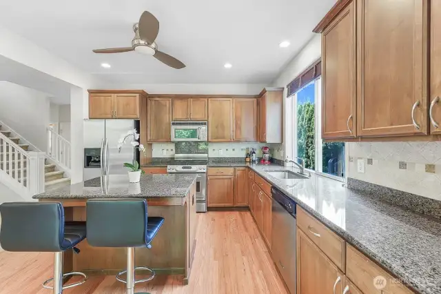 The kitchen features granite countertops, stainless steel appliances, and high ceilings.
