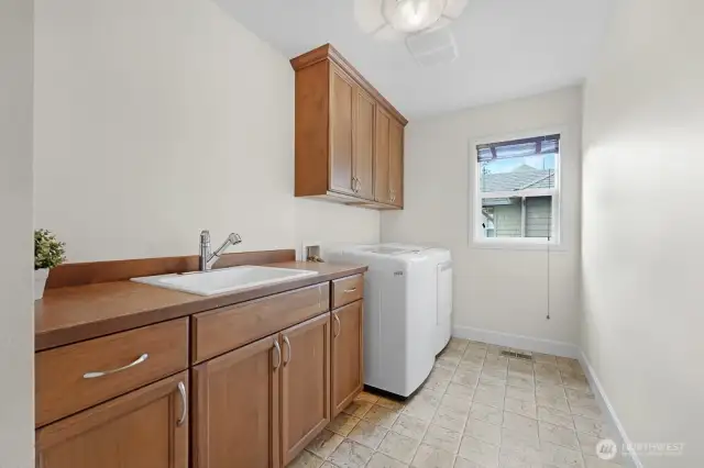 Second floor laundry room with cabinets and utility sink.