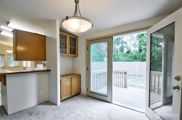 French doors off the dining area with another deck look out to the mature trees to the back of the home