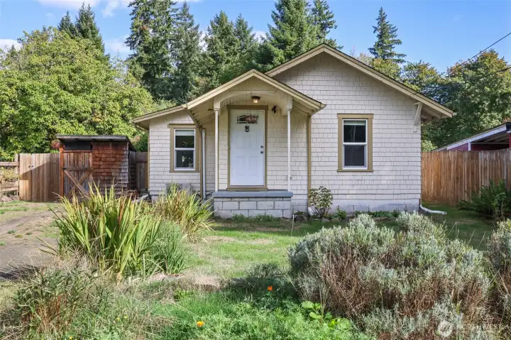 The shake siding and covered front stoop with curved ceiling are highlights of the 1930 style of this darling home.