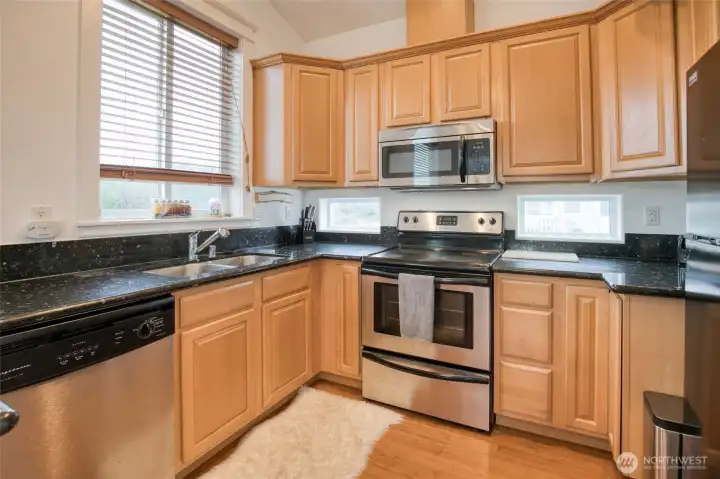 A closer look inside the kitchen shows stainless steel appliances, granite countertops, and plenty of workspace and storage.