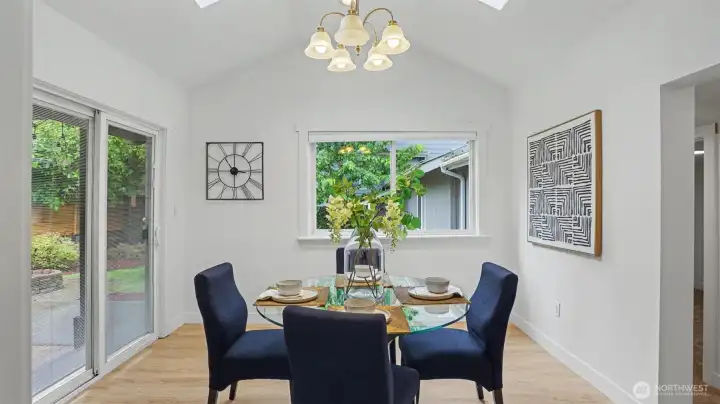 Dining area with vaulted ceilings and sliding door access to the outdoor space.