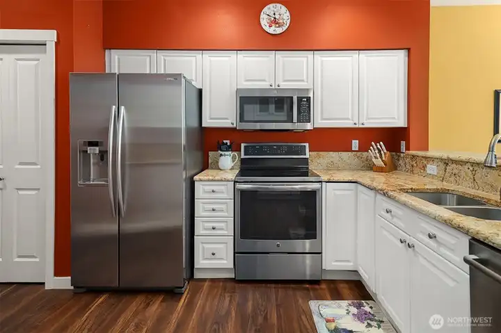 A kitchen pantry closet next to the refrigerator.  Microwave Oven over top of the Range / Oven