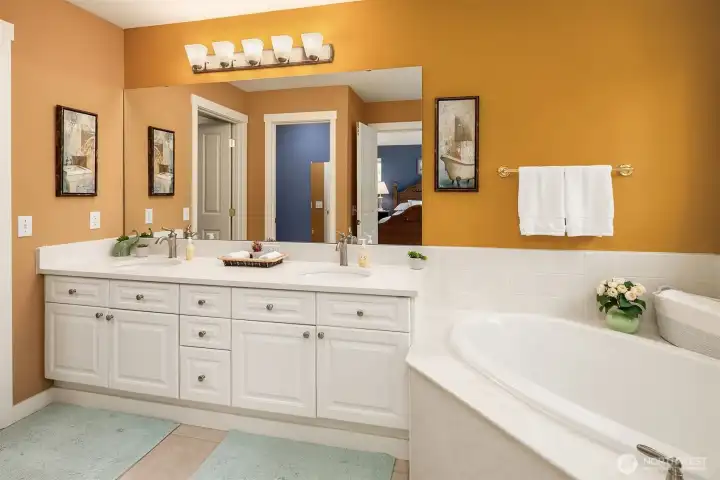 The primary bathroom has dual sinks, a corner bath tub, and separate shower