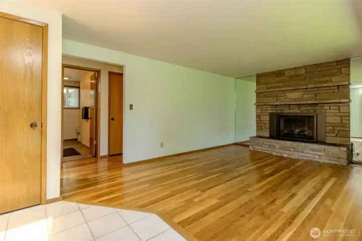 From the front entry, enter the living room with gorgeous hardwoods and a newer gas fireplace. In the distance, the main hall bath is visible.