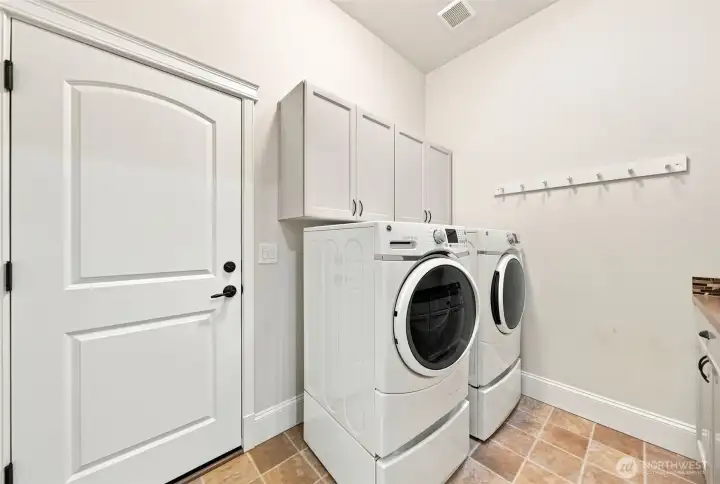 The laundry room has garage access, a solar tube to let in natural daylight, GE front load washer and dryer on stands for easy accessibility and extra storage, as well as more cabinets for additional storage. The 2 car garage has tons of storage and a utility sink.