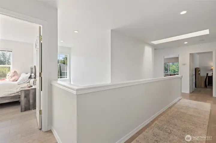 Hallway between bedrooms is open to below, and well lit by the skylight