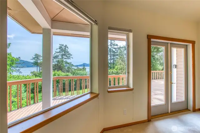 Primary bedroom suite is freshly painted with french doors, large windows, and vaulted ceilings.