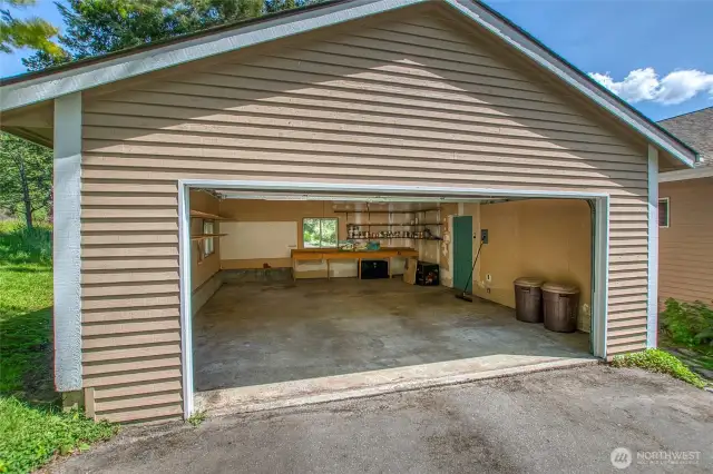 A large 2 car garage has a workbench and storage shelves. Plenty of room for projects.